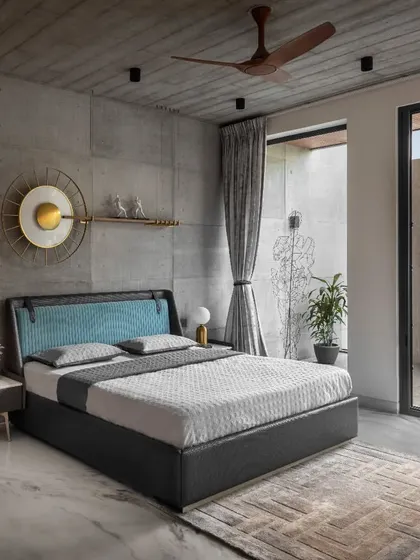 The master bedroom in Swatantra Residence has a minimalist, nature-inspired décor. The balcony's distinctive circular cutout provides privacy while serving as a unique architectural accent.