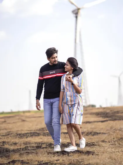 A classic walking shot, holding hands with the windmills behind them. It’s a simple, happy moment from their pre-wedding shoot.