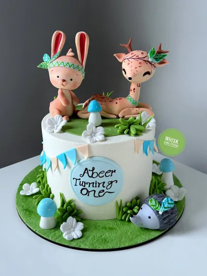 Cuteness overload with this woodland creatures cake. Perfect for a first birthday, it features an adorable handcrafted bunny, deer, and hedgehog.