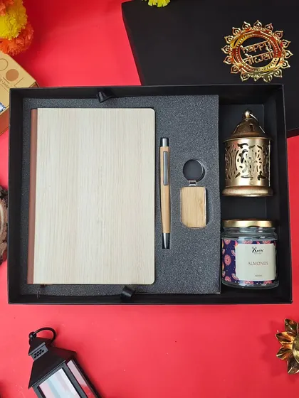 This Diwali gift set combines practicality with festive charm. It features a bamboo diary and pen set, a scented candle, a keychain, and a beautiful brass lantern, perfect for corporate gifting.
