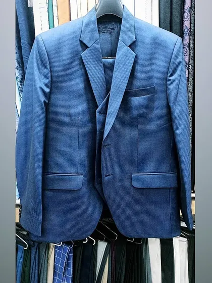 A finished blue three-piece suit hanging in my shop, ready for the client. The quality of the fabric and the cut are evident.