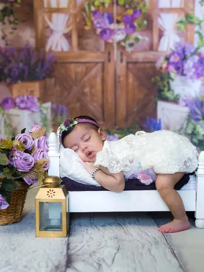 A wide shot of a newborn girl sleeping peacefully in a lavender-themed setup. The details and props come together to create a stunning, artistic image.