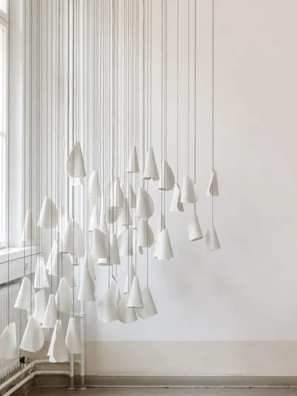 An installation of unlit Bocci 21 pendants, emphasizing their delicate, paper-like forms. The arrangement creates a beautiful play of shapes against the clean white walls.