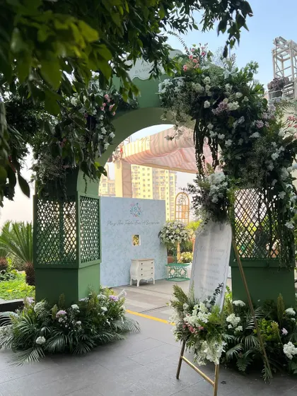 A serene welcome to a Haldi ceremony, with a green archway adorned with white and pink florals. The design sets a fresh, pure, and joyful tone.