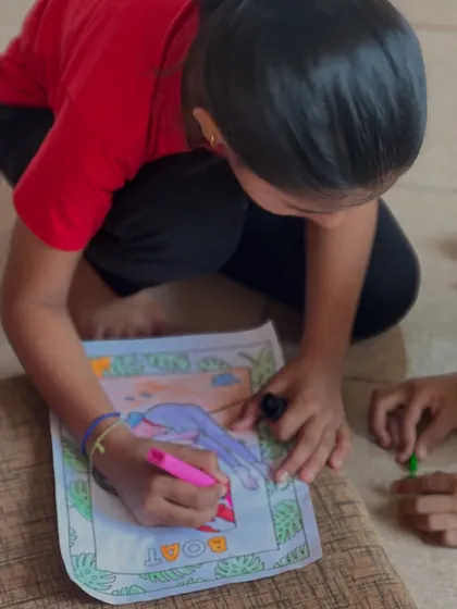 A young girl carefully colors a picture of the boat pose. This quiet activity helps develop concentration and reinforces their learning from the asana classes.