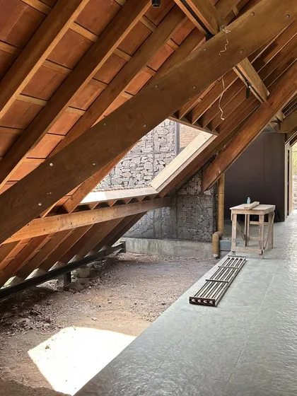 Light is sculpted and guided through the Alibaug residence. A carefully placed skylight in the wooden roof washes the stone wall with natural light, highlighting the texture of the materials and animating the corridor.