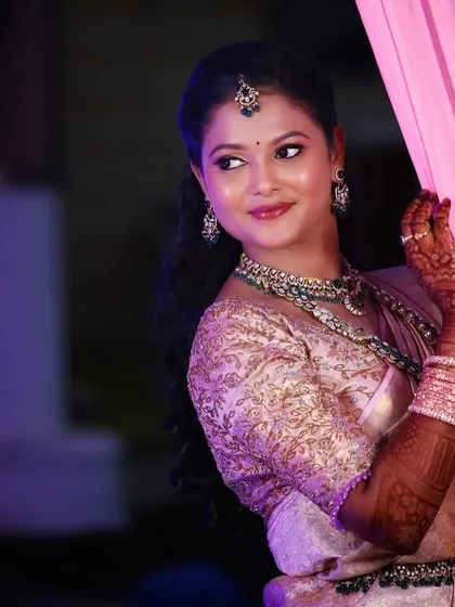 A candid moment of a bride during her reception. The lighting highlights her dewy makeup and the intricate details of her embroidered blouse and jewellery.