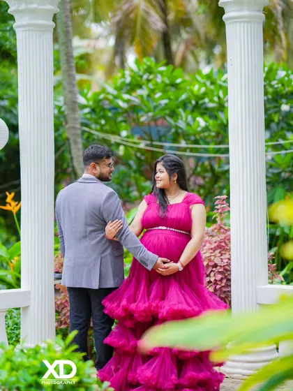 A romantic shot from behind, showing the couple walking hand-in-hand through a garden.