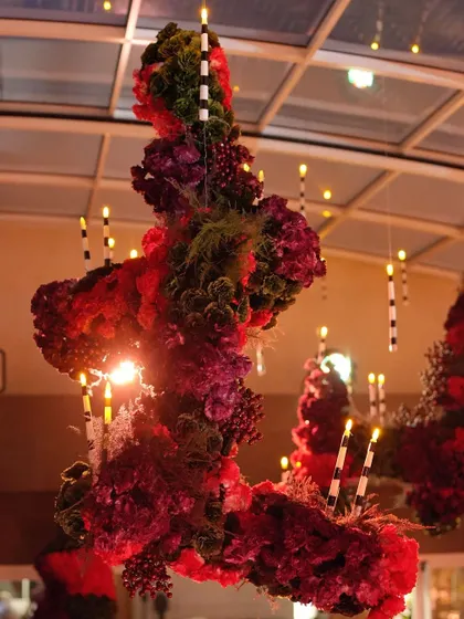 A stunning floral chandelier with hanging candles, creating a dramatic focal point in the red-themed space.