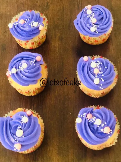 Simple and pretty vanilla cupcakes with a lovely purple whipped cream frosting and colourful sprinkles.