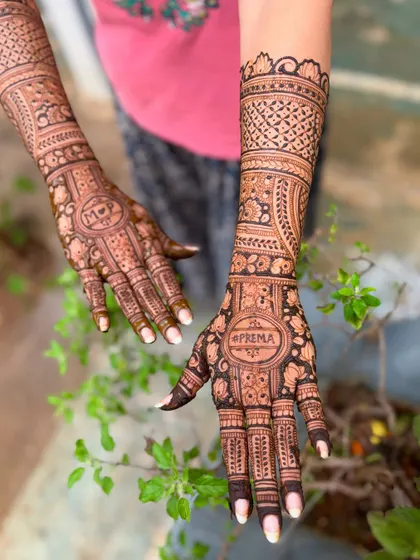 A personalized bridal mehendi for Prema, with her name and the couple's initials "M P" included in the design.