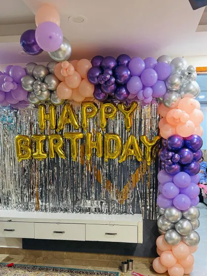 A close-up of the balloon arch and 'Happy Birthday' foil letters against a silver shimmer curtain.