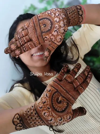 A happy client showing off her festive mehndi design, perfect for a sangeet or family gathering.