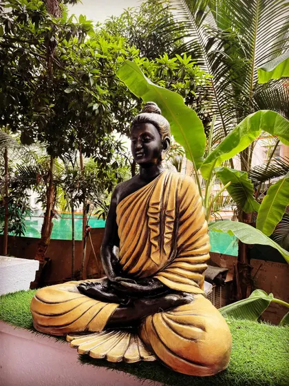 An angled shot of the Gautam Buddha fiber mural, highlighting the texture and finish that mimics traditional bronze and stone statues but with the benefits of lightweight fiber.