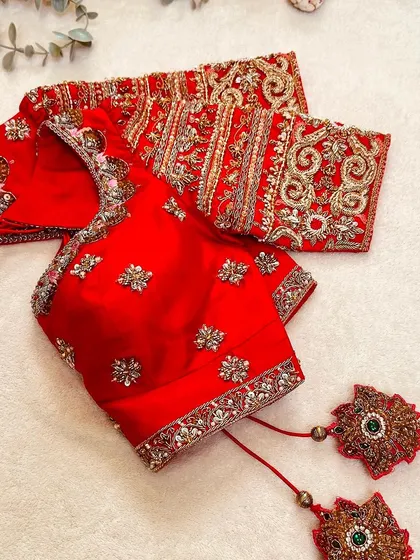 A closer look at the red Kanchi silk blouse, highlighting its sweetheart neckline and puff sleeves.