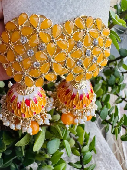 Bright and sunny, these yellow meenakari jhumkas are perfect for haldi or mehendi functions. The enamel work is detailed with hints of red and white, adding a unique touch.