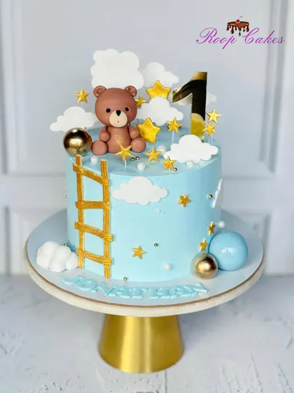 One year of sweet moments and endless joy. This first birthday cake features a teddy bear climbing a golden ladder to the stars.