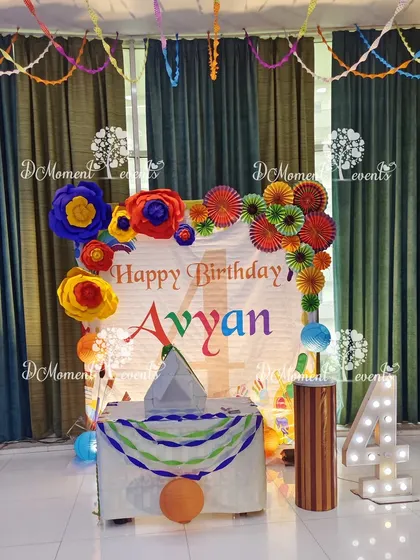 The cake-cutting area for the Art & Craft party, featuring a backdrop decorated with handmade paper flowers and pinwheels.