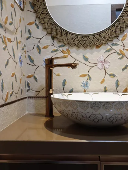 A close-up of a beautifully detailed wash area. The design features a floral mosaic tile backsplash, a patterned ceramic vessel sink, and a bronze-finish tap for a touch of traditional elegance.