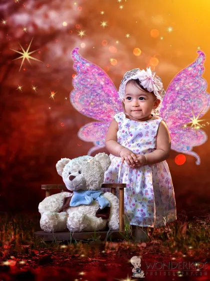 A baby girl with sparkling fairy wings, sitting with her teddy bear in a magical, glowing forest. This photo combines portraiture with digital art to create a truly enchanting image.