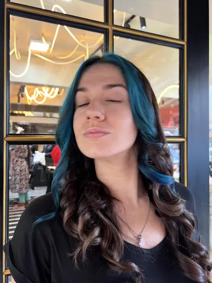 A beautiful result of blue face-framing highlights on a dark base. The color is bold but sophisticated, styled with soft curls.