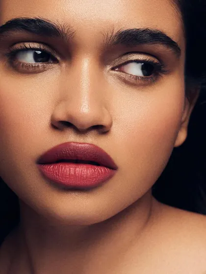 A close-up on a classic red lip. The skin around the lips is kept clean and luminous, allowing the bold lip color to be the hero of this timeless look.