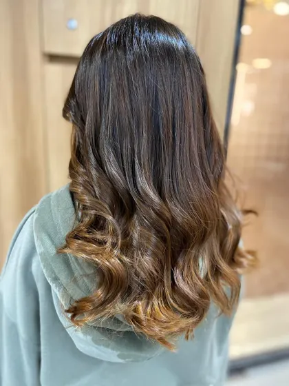 The final result of our color correction service. The hair is now a beautiful, multi-tonal brown with soft waves, looking healthy, vibrant, and completely revitalized.