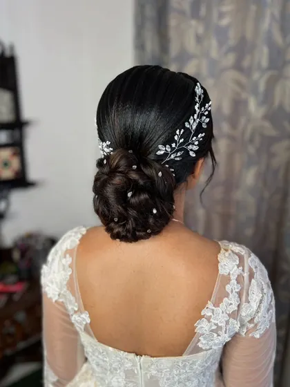 A classic low bun for a Christian bride, adorned with a sparkling crystal vine accessory. This look is elegant, timeless, and perfect for a white wedding gown.