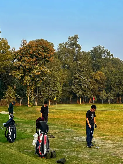 Young golfers practice their short game on the green during a golden hour session.