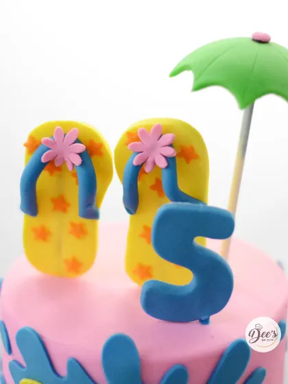 The fondant flip-flops and beach umbrella on top add a playful touch to this summer-themed cake.