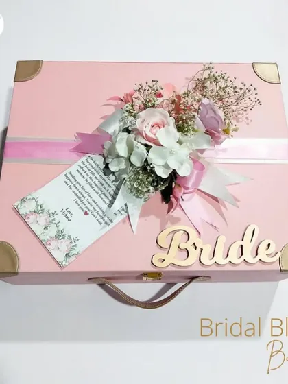 The 'Bridal Bliss Bundle'. This elegant pink trunk, personalized with "Bride" in a wooden cutout, is the perfect way to present a collection of thoughtful gifts.