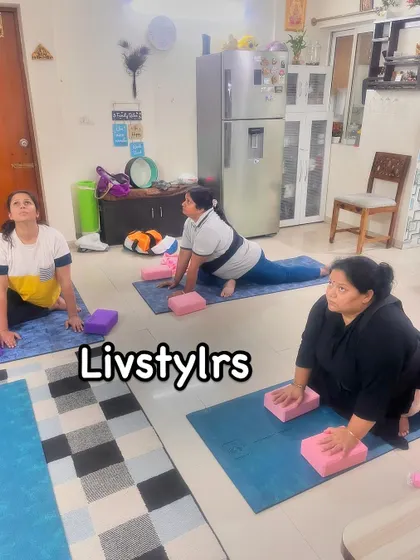 A group of clients practice pigeon pose with blocks for support. This modification helps to make the deep hip stretch more accessible and comfortable for different body types.