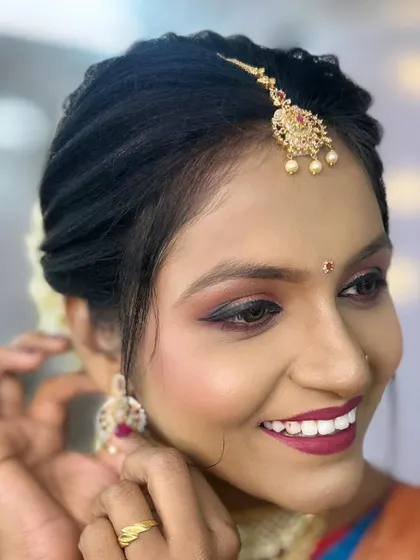 A close-up showing the flawless makeup and the model adjusting her earring.