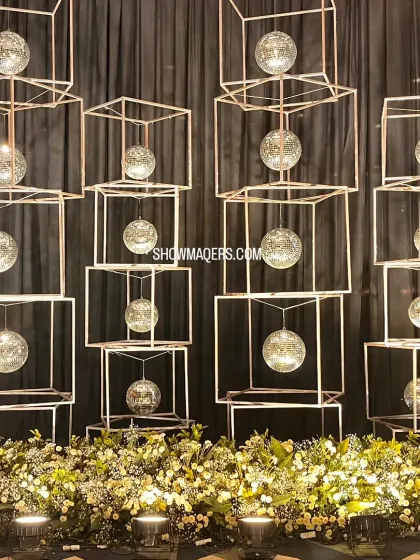 A modern art installation featuring suspended disco balls in geometric frames, serving as a unique decor element for a cocktail party.