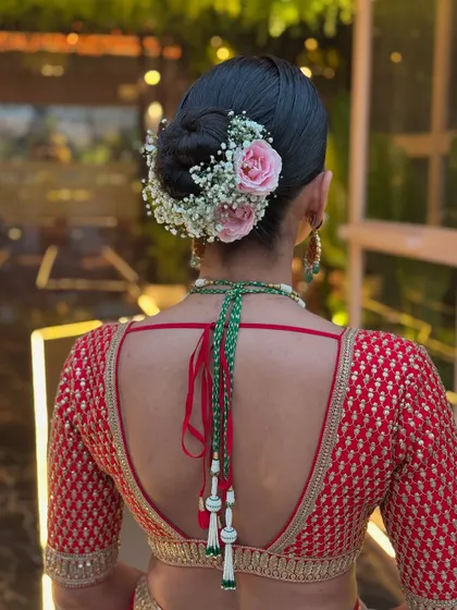 For this bride's look, I combined delicate pink roses with baby's breath to create a soft floral halo around her sleek bun. This style adds a touch of romance and is perfect for coordinating with the colors in a bridal lehenga.