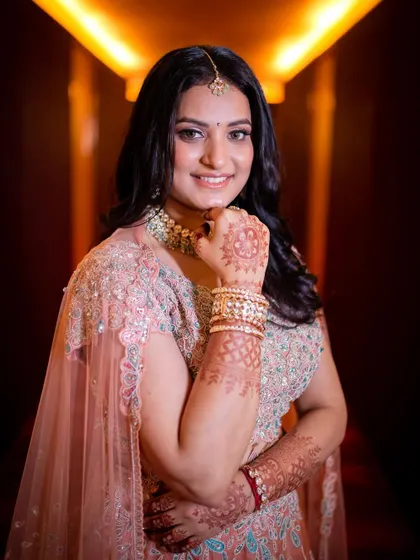 A beautiful portrait of the bride-to-be in her engagement lehenga, smiling brightly in a warmly lit corridor.