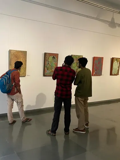 Visitors at the 'ME, AMMA, WE' exhibition, looking at the vibrant paintings by Devu Nenmara.