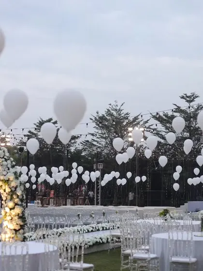A sky full of white balloons adds a touch of whimsical magic to this dreamy white wedding setup.