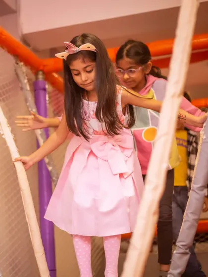 A girl carefully navigates the rope bridge in our multi-level play structure. It's a fun challenge that builds confidence.