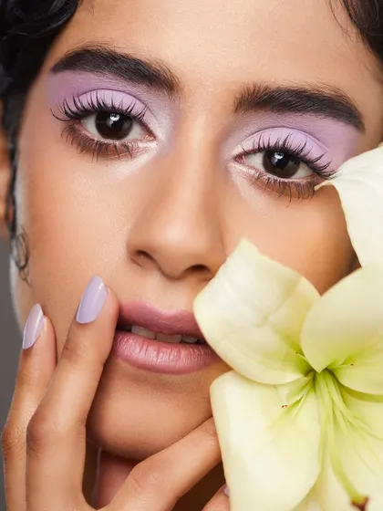 A soft and dreamy look with pastel lavender eyeshadow, paired with a matching manicure and a beautiful white flower.