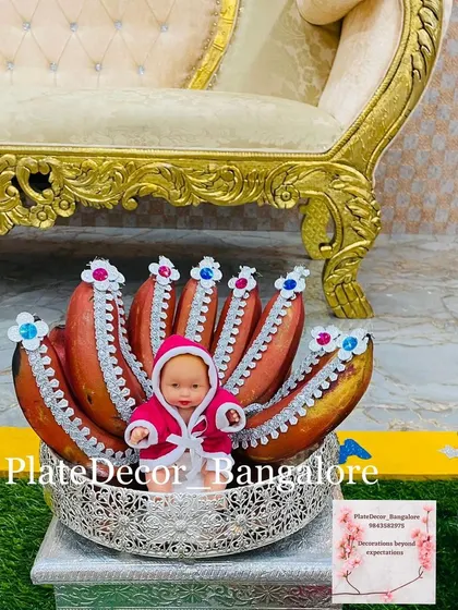 A unique platter for a baby shower, where I've decorated a bunch of red bananas with silver lace and placed a baby doll in the center.