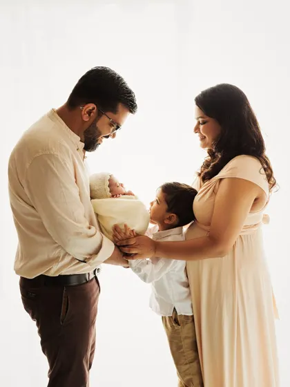 A beautiful family portrait with a big brother looking lovingly at his new sibling. A heartwarming image of a family of four.