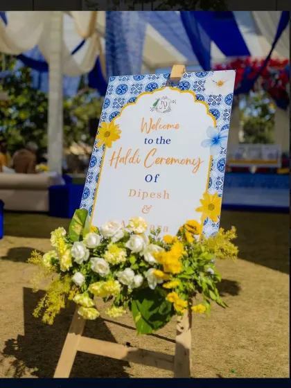 A close-up of the elegant welcome signage for the Haldi ceremony, framed with fresh yellow and white flowers.