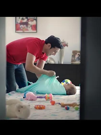 Another shot from the baby care campaign, showing me swaddling the baby. These scenes are designed to be authentic and emotionally resonant for parents watching the ad.