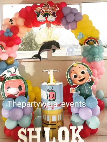 A Cocomelon party with a cable car prop and a rainbow balloon arch.