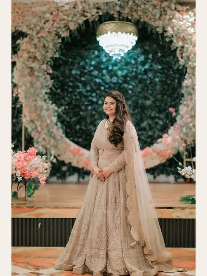 A beautiful portrait of the bride standing before a circular floral arch. The grand decor and her graceful pose create a picture-perfect image of bridal elegance.