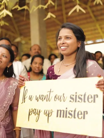 "If you want our sister, pay up mister!" The bride's side playfully welcoming the groom with fun signs and demands, a cherished part of many South Indian weddings.