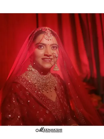 An artistic bridal portrait taken through her sheer red veil. The soft focus and rich red tones create a dreamy and romantic image.