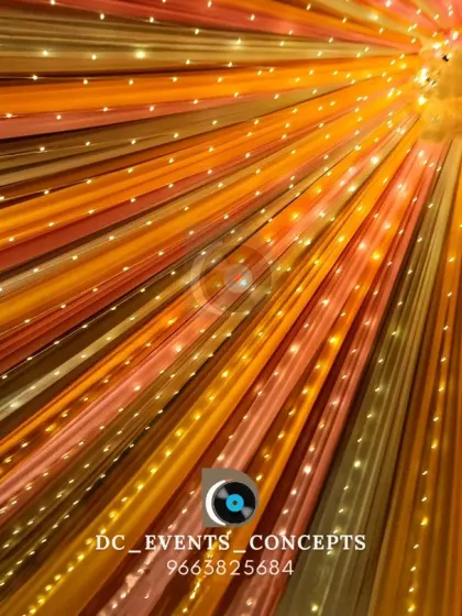 A look up at a colorful ceiling decoration made of draped fabric and embedded fairy lights. This design adds vibrancy and warmth to the entire venue.