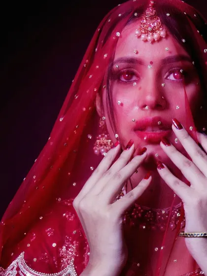 A close-up, artistic bridal portrait looking through a sequined veil. This experimental shot plays with color and texture, offering a modern and slightly edgy take on bridal beauty photography.